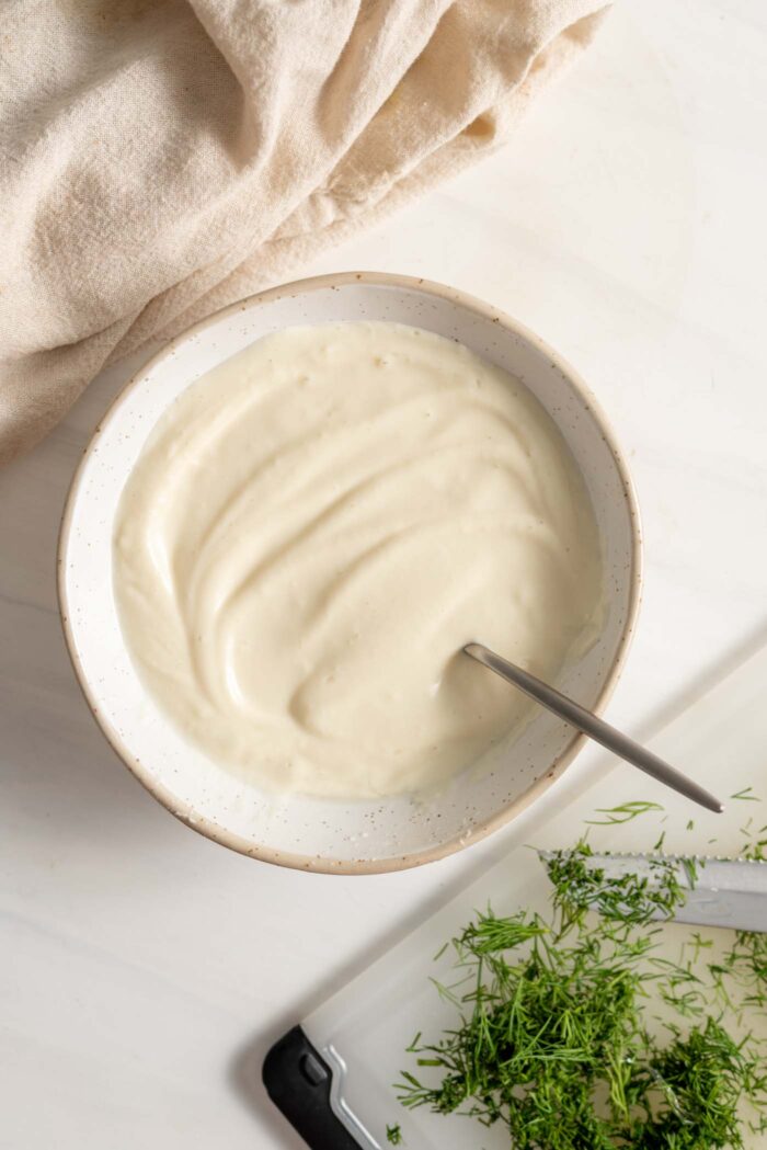 A creamy white sauce in a bowl with a spoon.