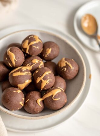 Chocolate energy balls drizzled with peanut butter in a bowl.