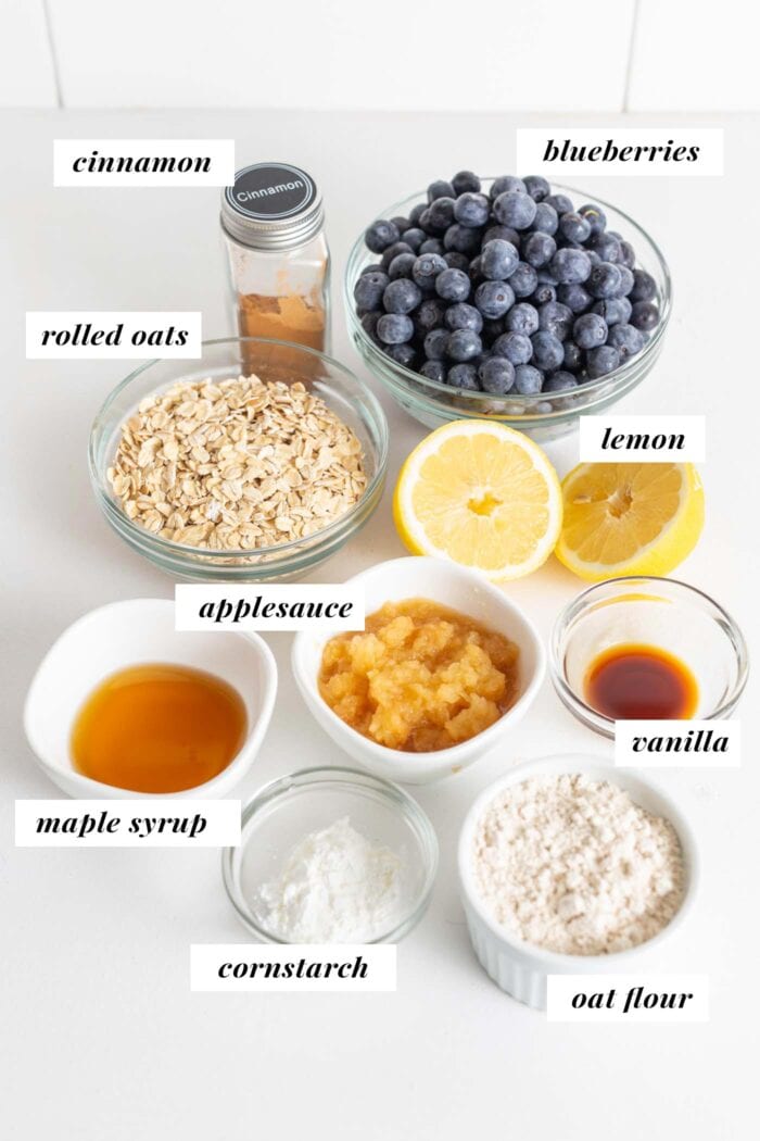 Blueberries, oats, oat flour, cinnamon, applesauce and maple syrup in dishes on a counter.