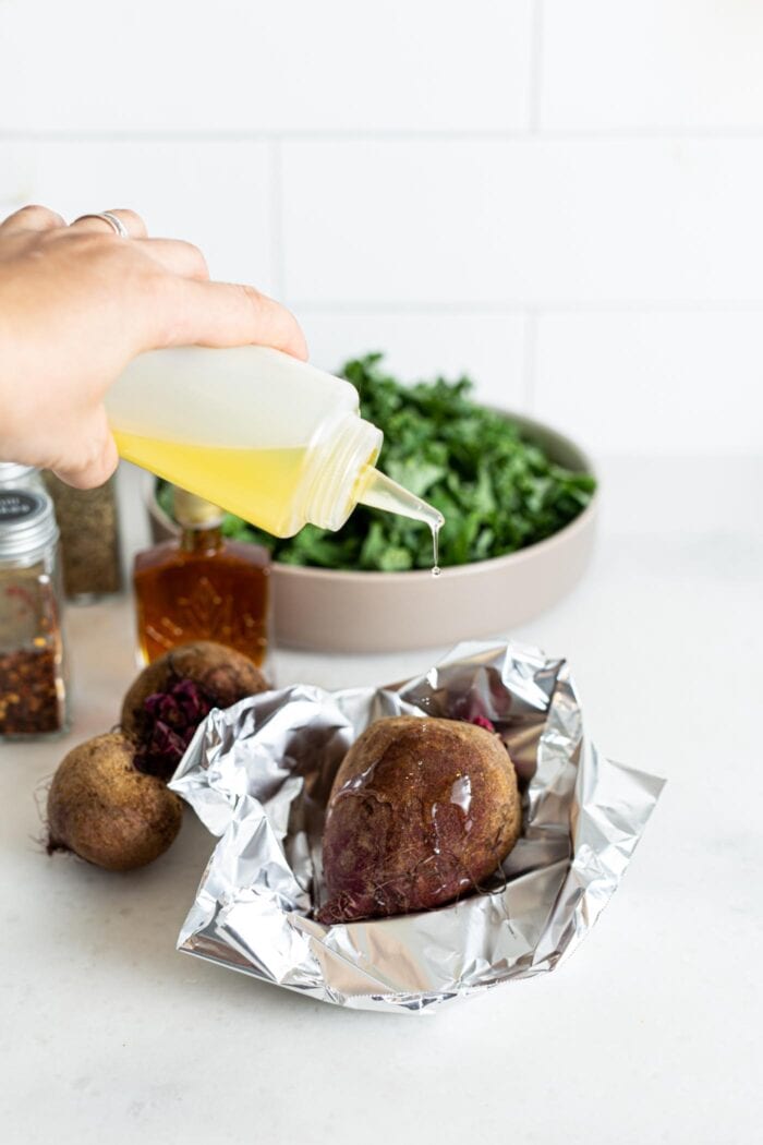 Adding olive oil to a beet wrapped in foil.