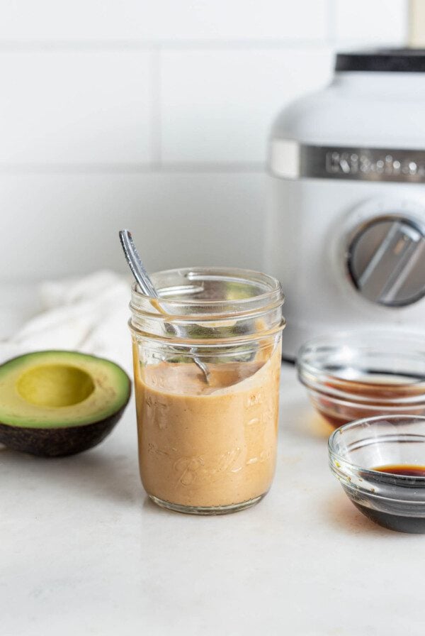 A jar of spicy mayo sauce with a spoon in it.