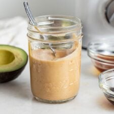 A jar of sauce with a spoon in it.