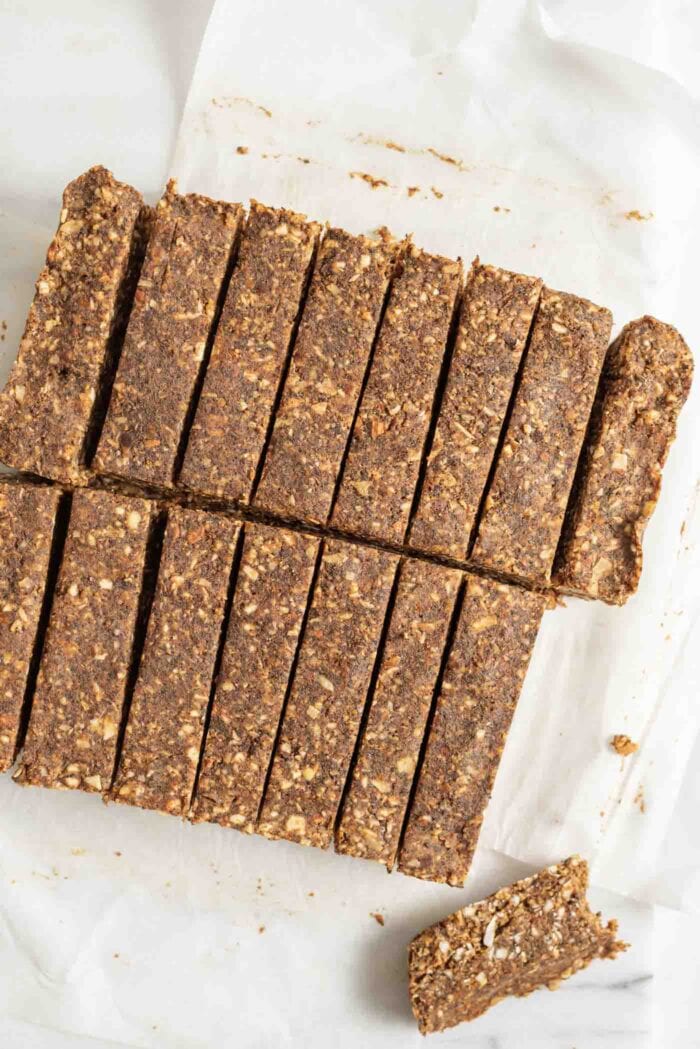Raw energy bars sliced into 16 pieces on a piece of parchment paper.