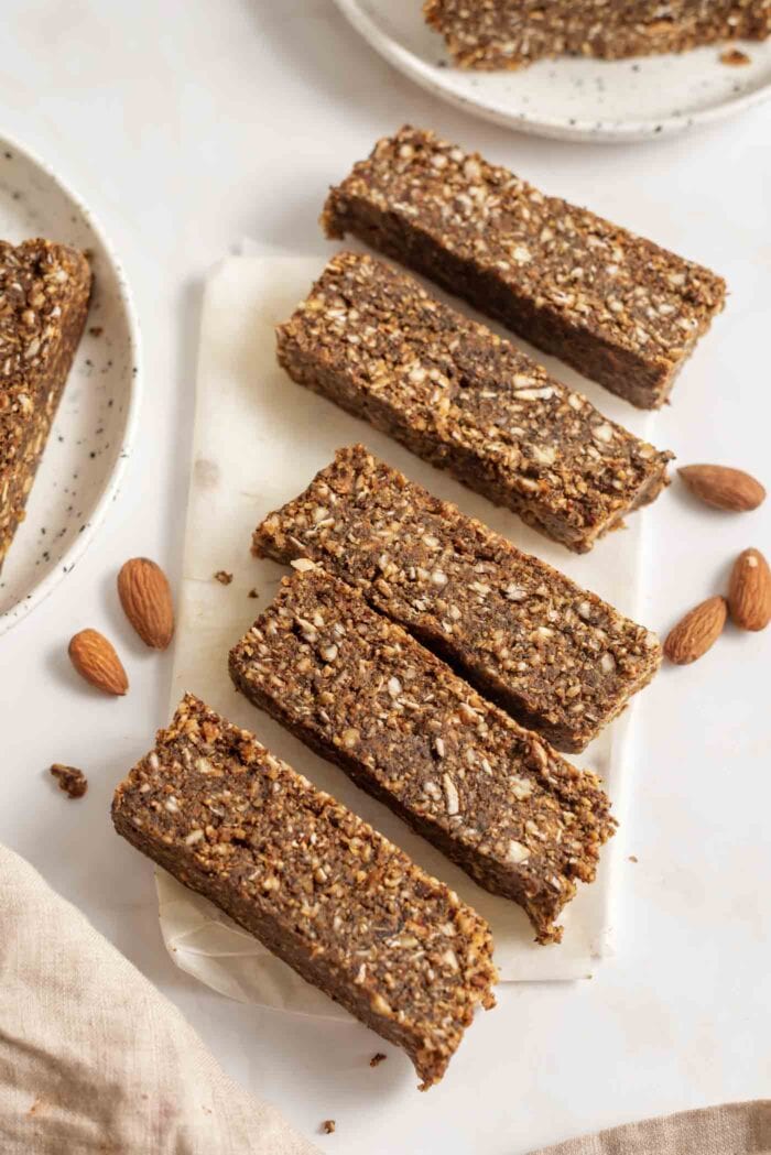 5 thick slices of energy bars on parchment paper with some almonds scattered around.