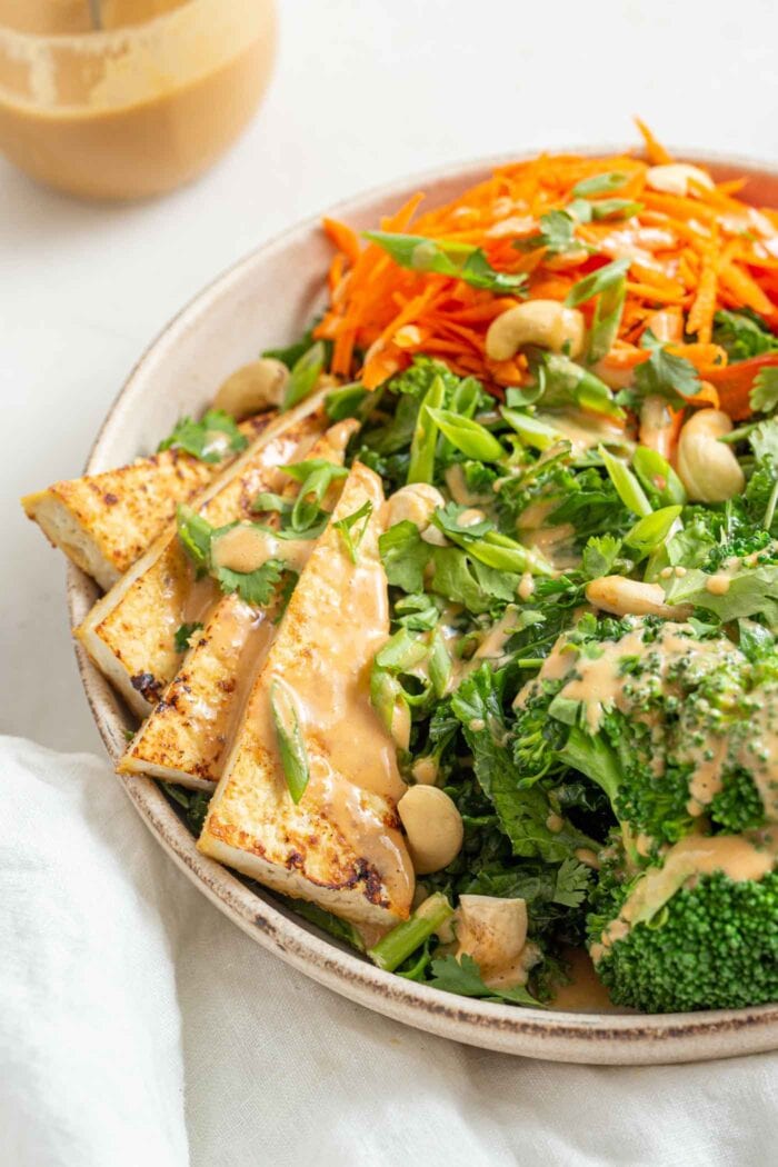 Large triangles of crispy tofu in a salad with kale and broccoli.