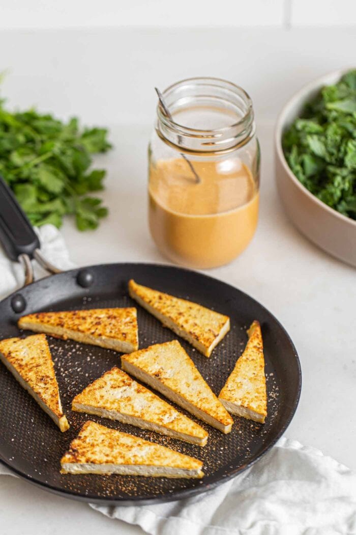 Browned tofu triangles in a skillet on a counter.