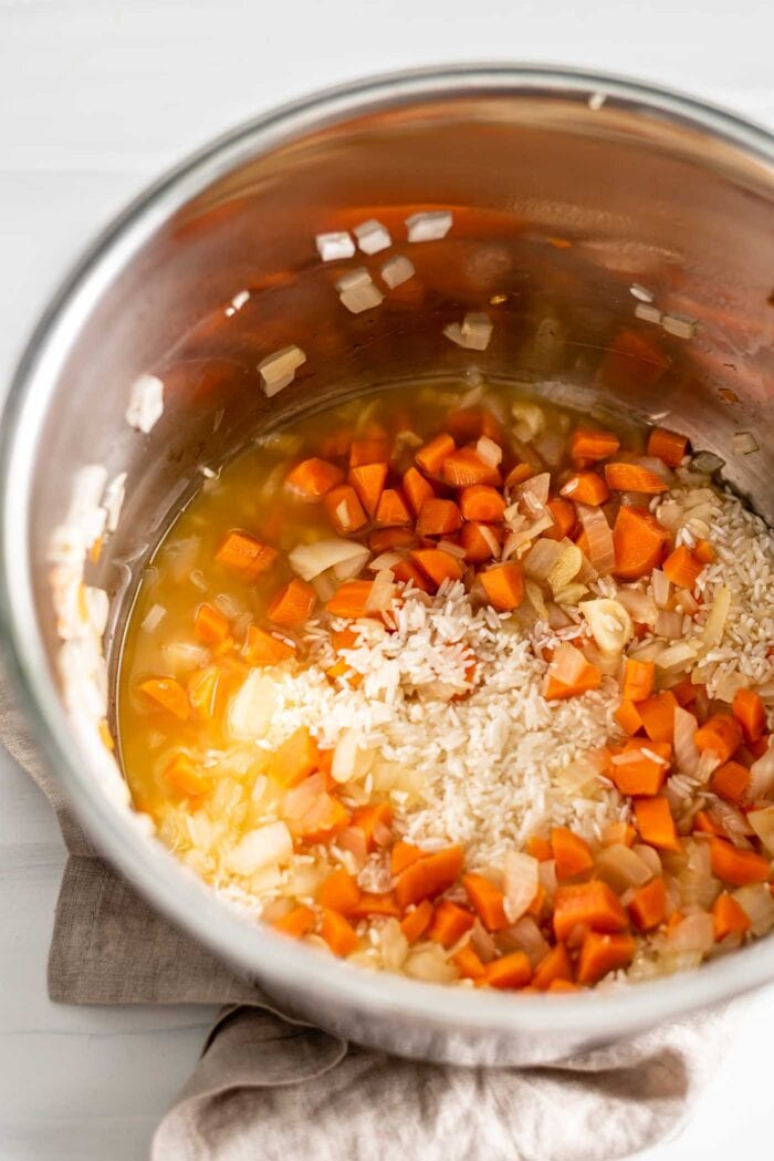 Rice, broth, carrots and onion in an Instant Pot.