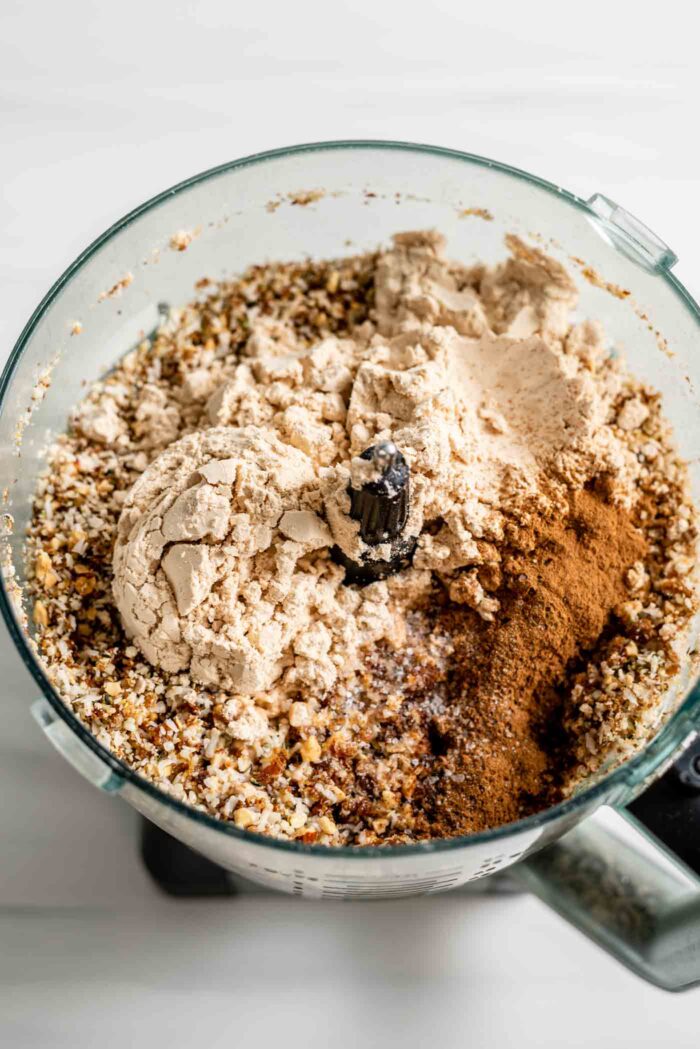 Protein powder, cinnamon in a food processor with a crumbly nut mixture.