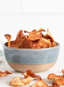 Bowl of baked apple chips with cinnamon on them.
