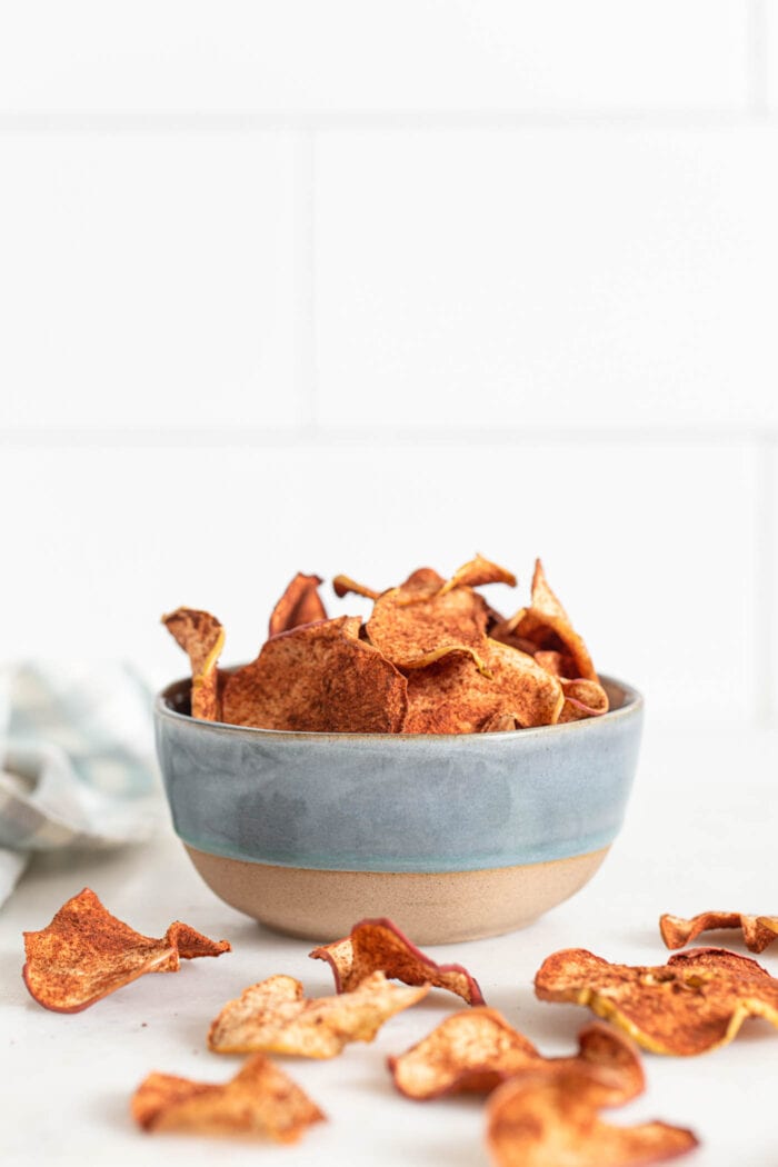 Bowl of baked apple chips with cinnamon on them.