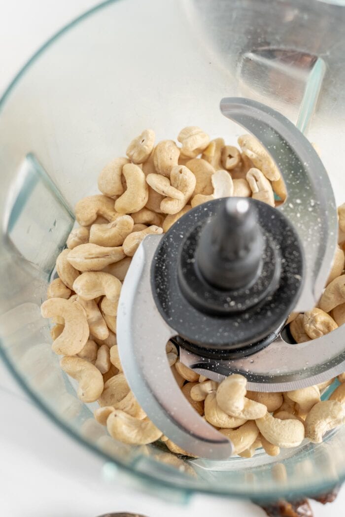 Raw cashews in a food processor container.