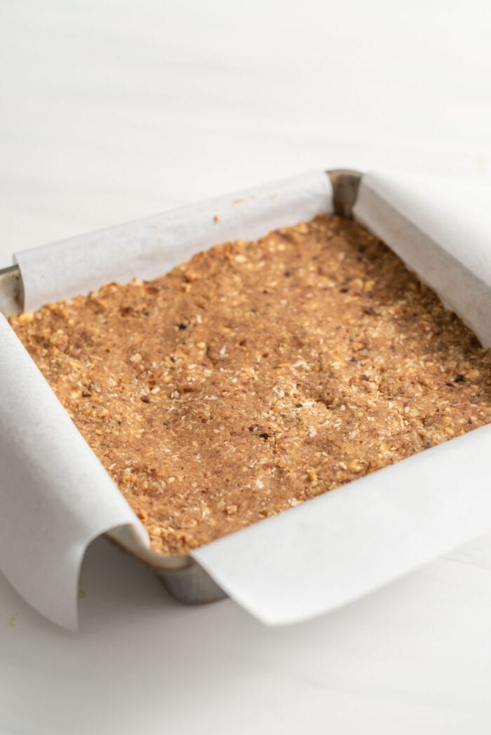 Parchment paper-lined square baking pan of energy bars.