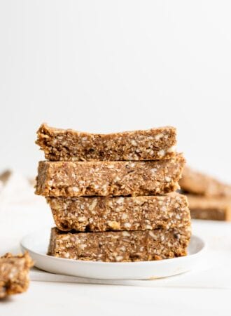 Stack of 4 energy bars on a small plate. More bars in foreground and background.