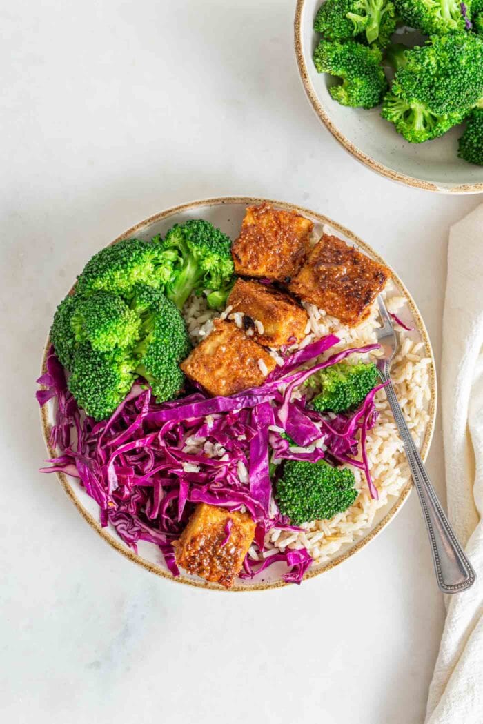 Buddha bowl with broccoli, brown rice, tempeh and thinly sliced red cabage.