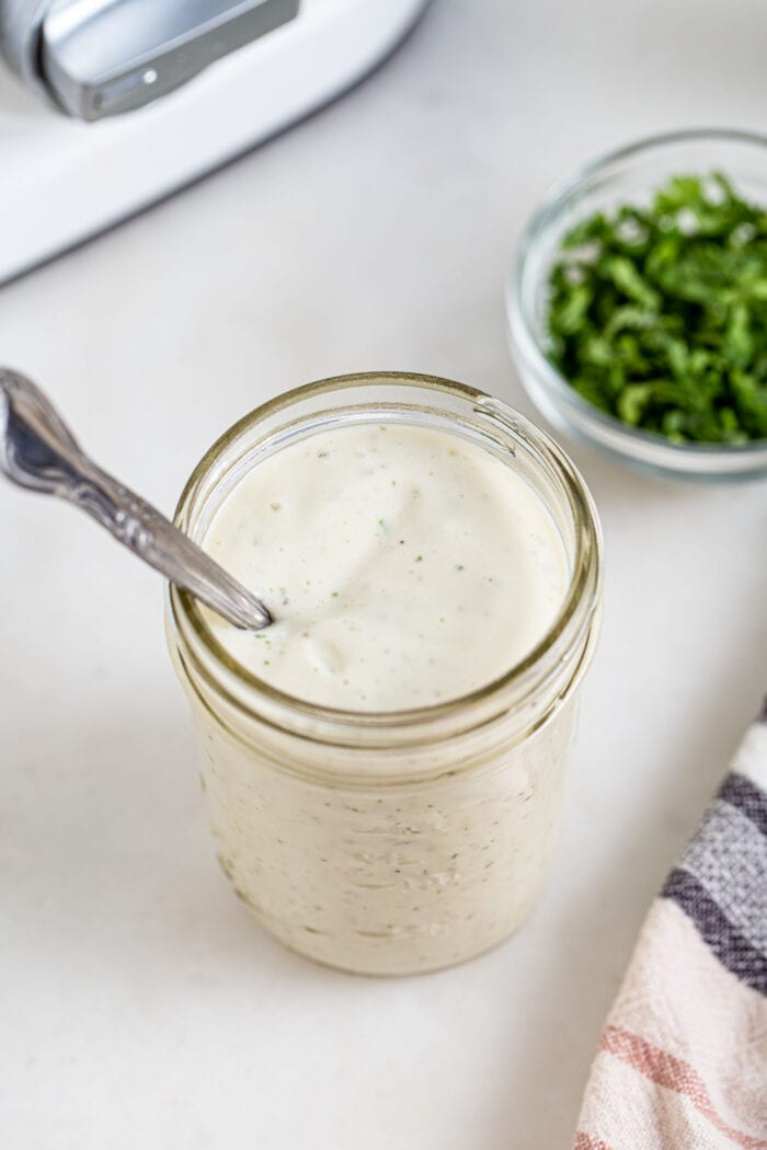 Jar of creamy ranch sauce with a spoon in it.