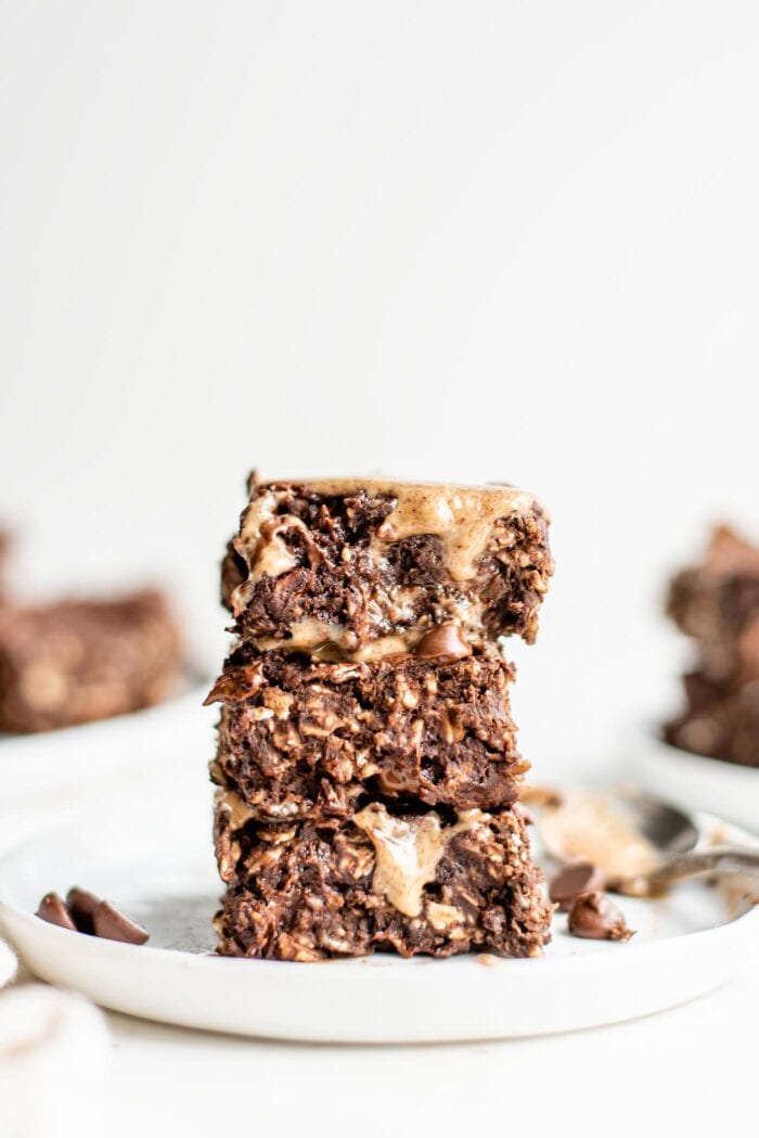 Stack of 3 baked double chocolate chip oatmeal bars on a plate.