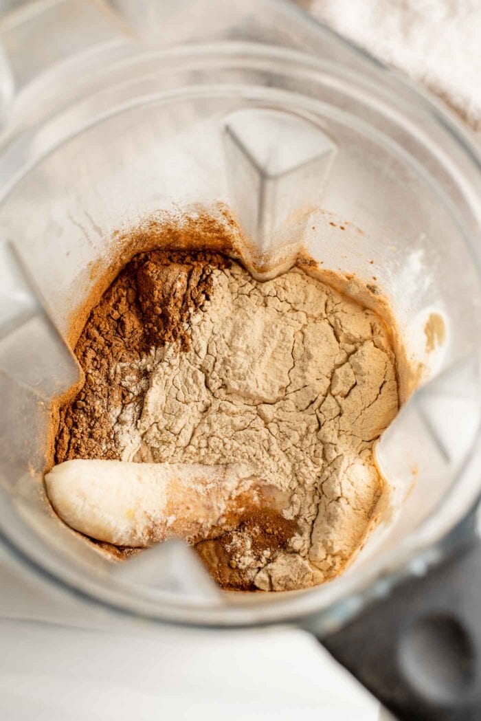 Milk, banana, cinnamon and protein powder in a blender container.