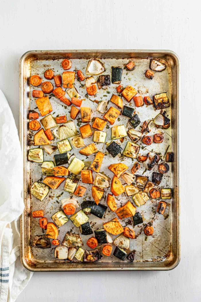 Roasted sweet potato, onion, carrot and zucchini on a baking tray.