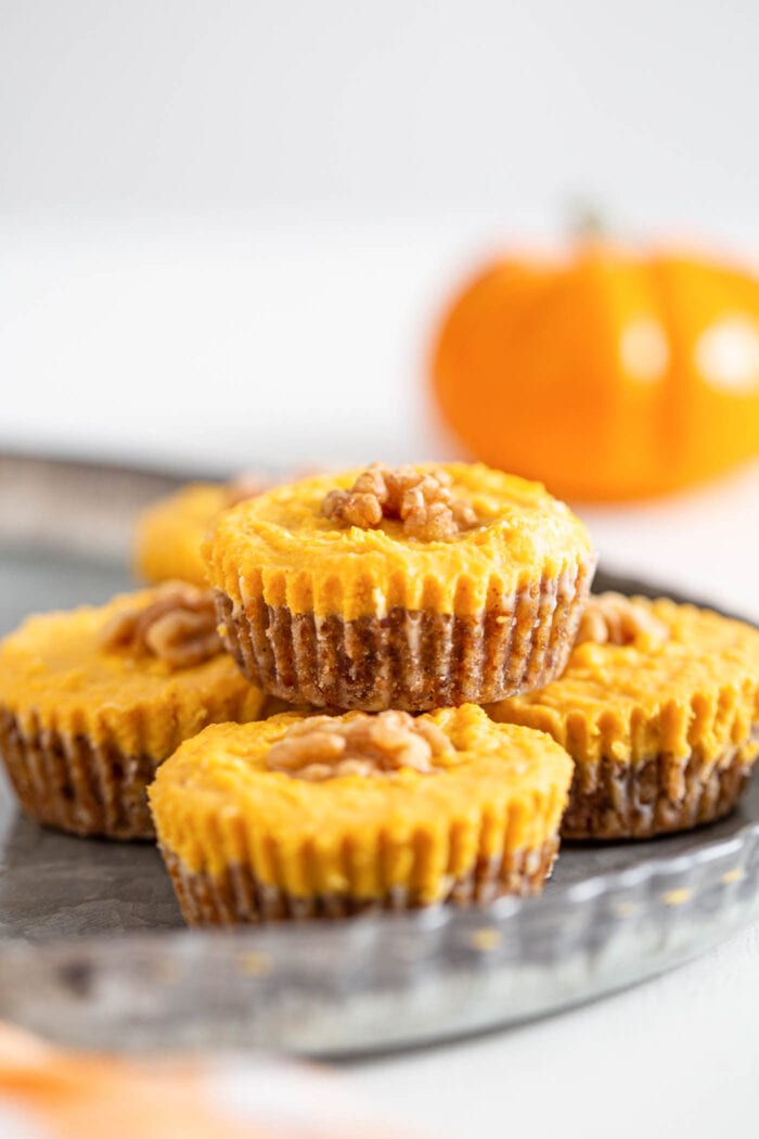 5 no-bake mini pumpkin pie tarts on a metal serving tray with a mini pumpkin in the background..
