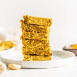 Stack of 6 turmeric coconut and cashew energy bars on a small plate.