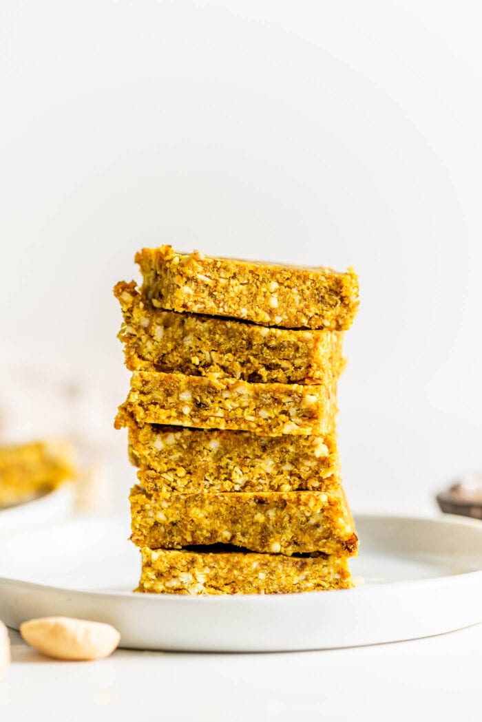 Stack of 6 turmeric coconut and cashew energy bars on a small plate.