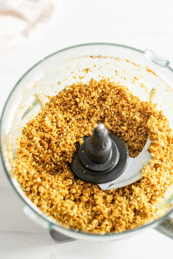 A crumbly coconut and turmeric mixture blended up in a food processor container.