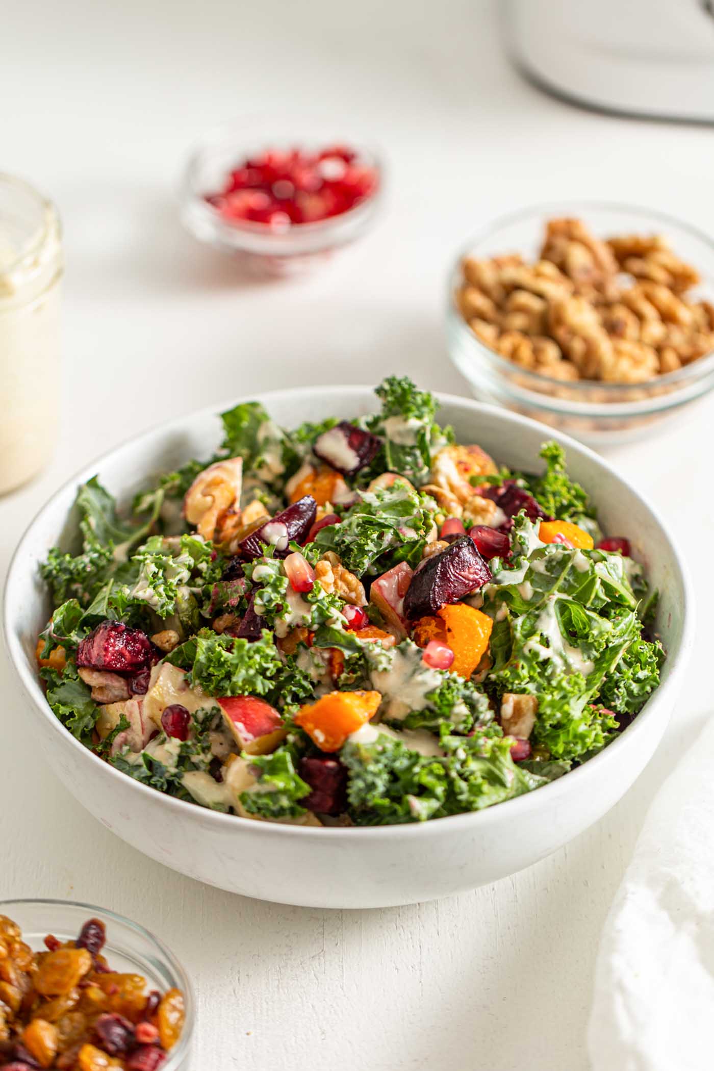 Bowl of kale salad with squash, beets, brussels sprouts, walnuts and pomegranate.