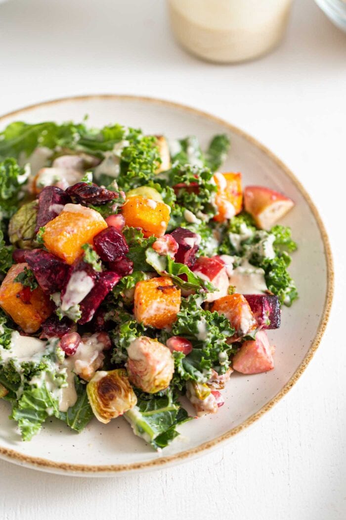 Colourful Fall salad with kale, roasted vegetables and tahini sauce on a plate.