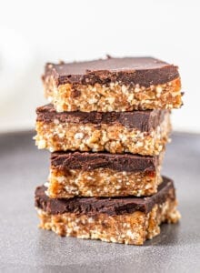 Stack of 4 chocolate coated cashew bars on a plate.