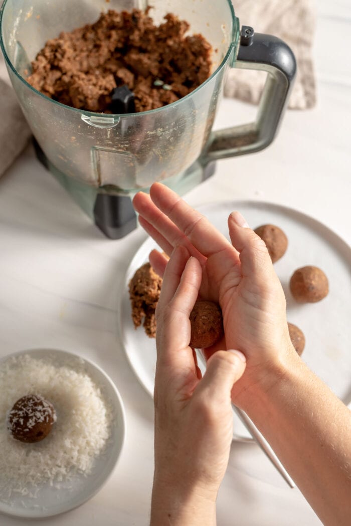 Two hands rolling dough into energy balls.