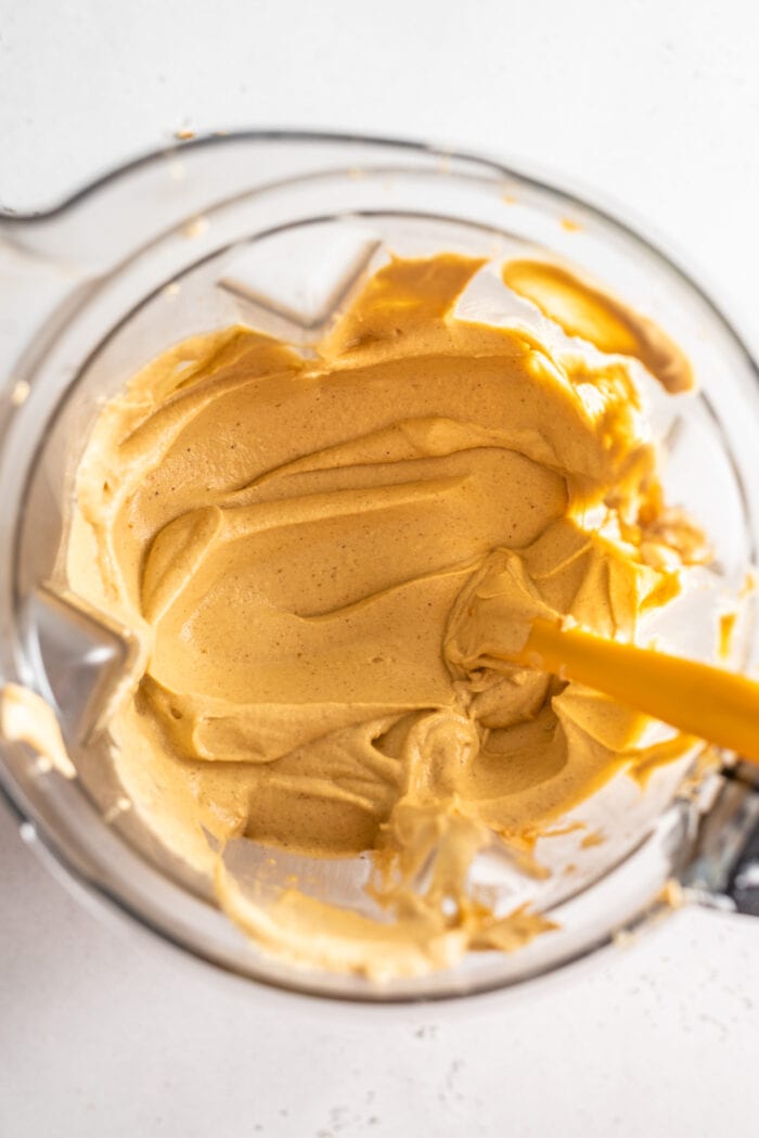 A creamy, smooth, orange mixture in a high-speed blender. Spatula rests in blender.