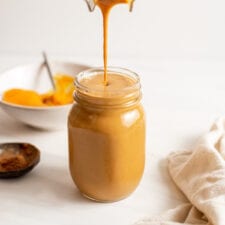 Blender pouring a pumpkin smoothie into a glass jar.