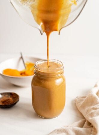 Blender pouring a pumpkin smoothie into a glass jar.