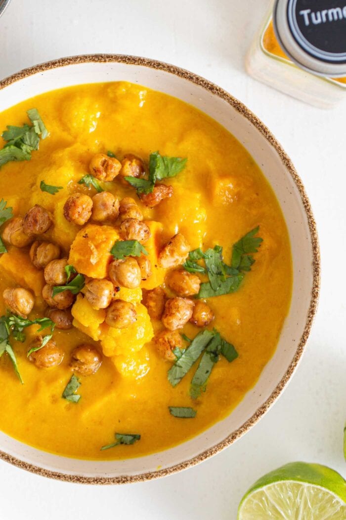 Overhead view of a bowl of chunky sweet potato cauliflower soup topped with chickpeas and cilantro.