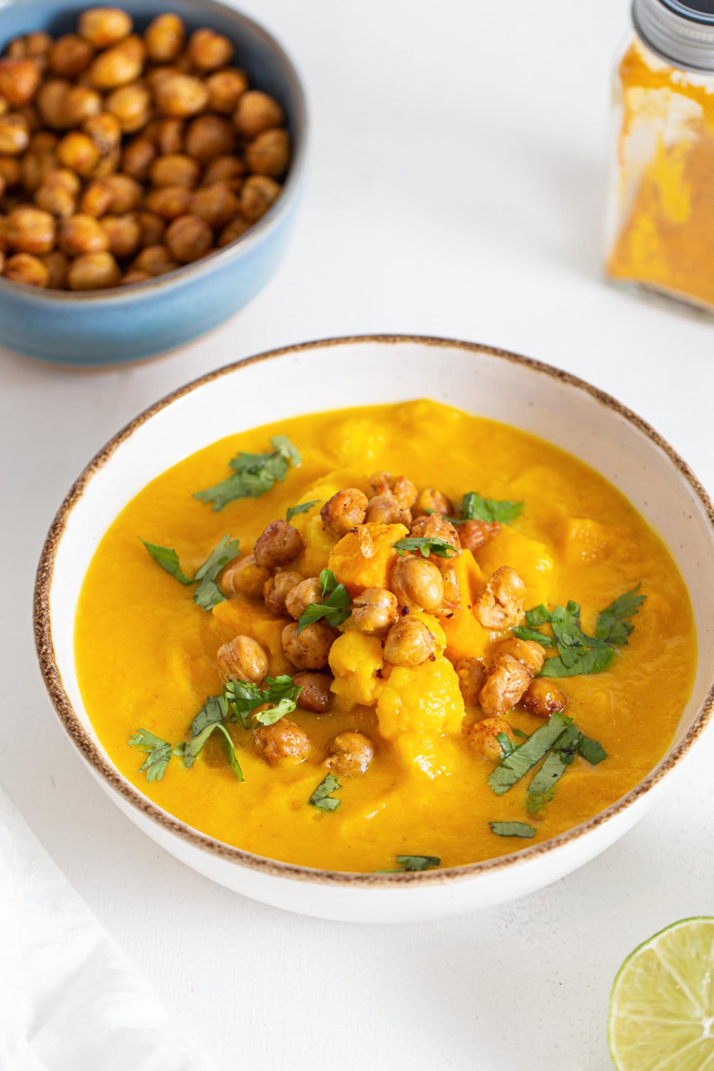 Bowl of sweet potato cauliflower soup topped with chickpeas and cilantro.