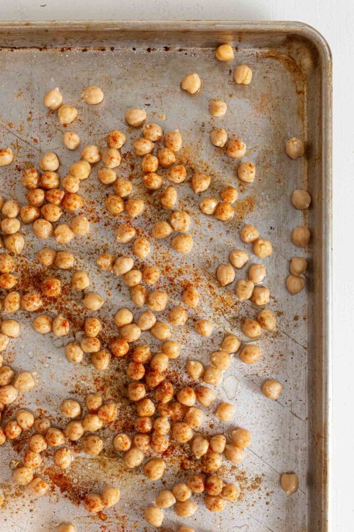 Overhead view of chickpeas on a pan tossed with spices.