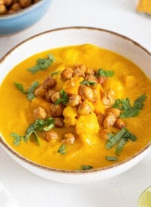 Bowl of sweet potato cauliflower soup topped with chickpeas and cilantro.