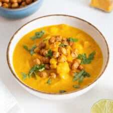 Bowl of sweet potato cauliflower soup topped with chickpeas and cilantro.