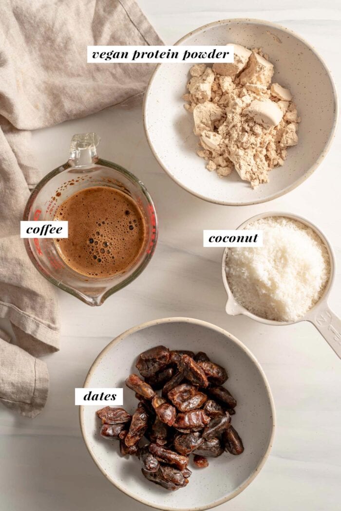 Dates, coffee, coconut and protein powder in bowls. Each ingredient is labelled with text overlay.
