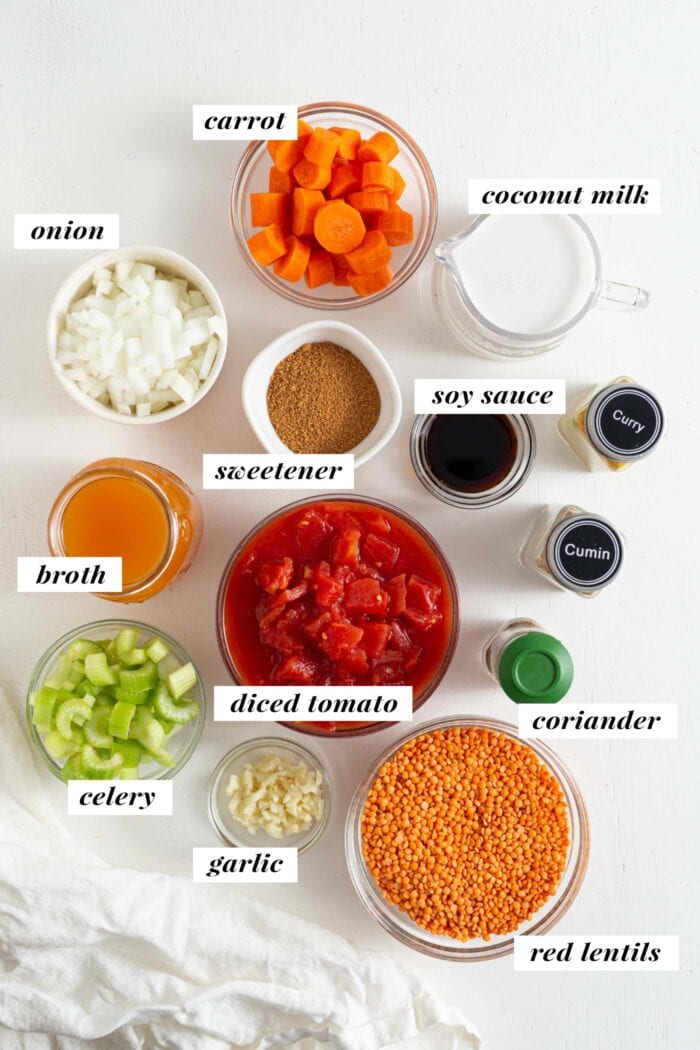 Overhead view of labelled ingredients needed for making a curried red lentil soup.