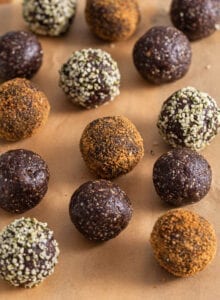 Chocolate energy balls rolled in coconut sugar and hemp seeds on a cutting board lined with parchment paper.