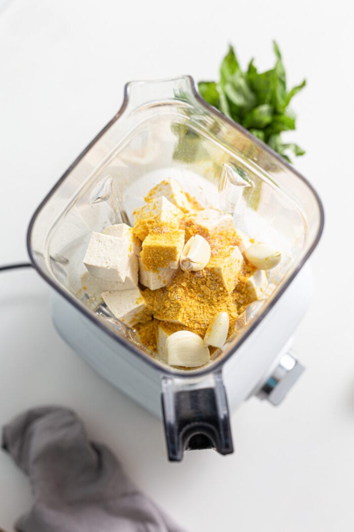 Chunks of tofu and nutritional yeast in a blender.