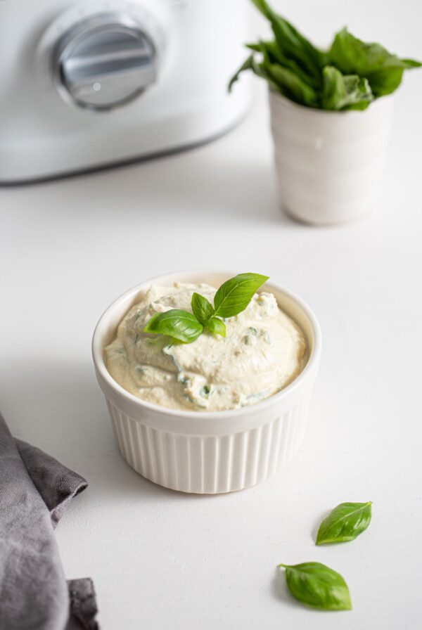 Small dish of herb ricotta topped with a piece of fresh basil.