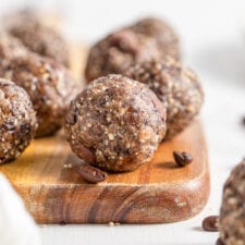 Close up of a chocolate chip energy ball on a cutting board. More balls in background.