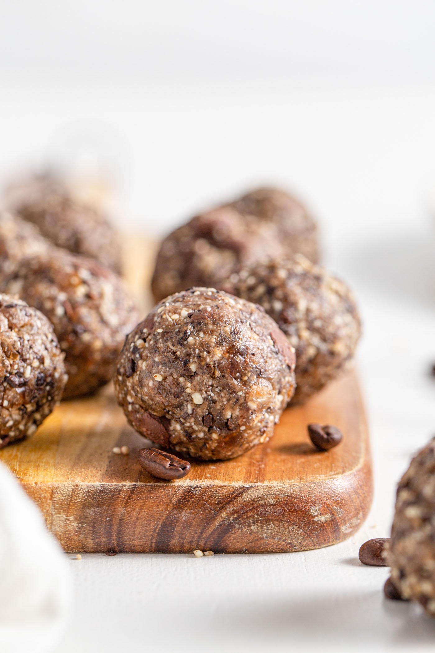 A chocolate chip energy ball on a cutting board. More balls in background.