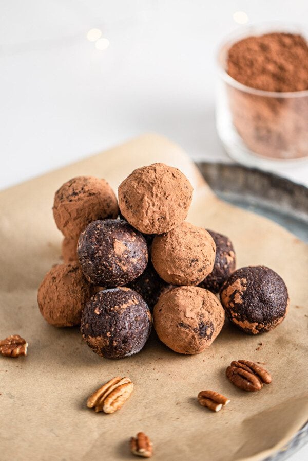 Stack of rum balls on a parchment paper lined plate.