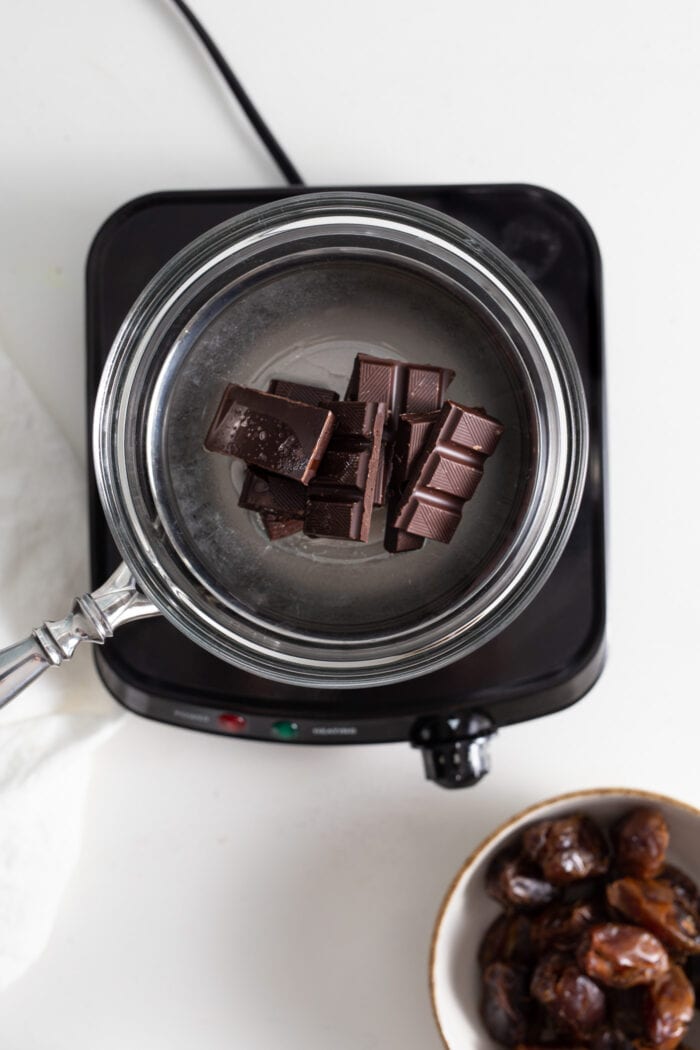 Dark chocolate in a double boiler on a small cooktop.