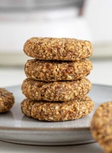 Stack of 4 tahini oat cookies on a plate. 2 cookies rest beside the stack on the plate.