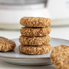 Stack of 4 tahini oat cookies on a plate. 2 cookies rest beside the stack on the plate.