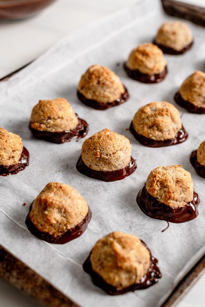 Chocolate dipped macaroons on a baking tray lined with parchment paper.